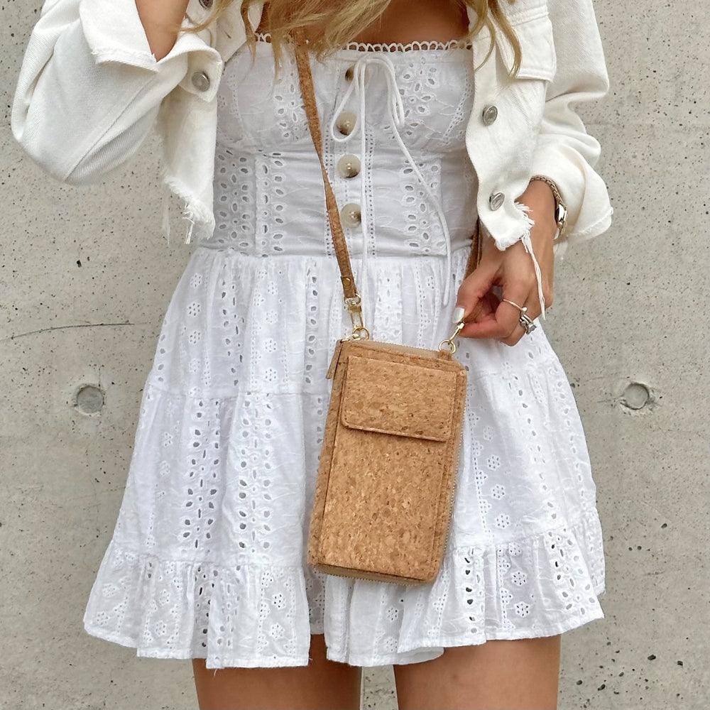Model in white dress wearing By The Sea Collection, Nyla, classic cork cross body phone bag