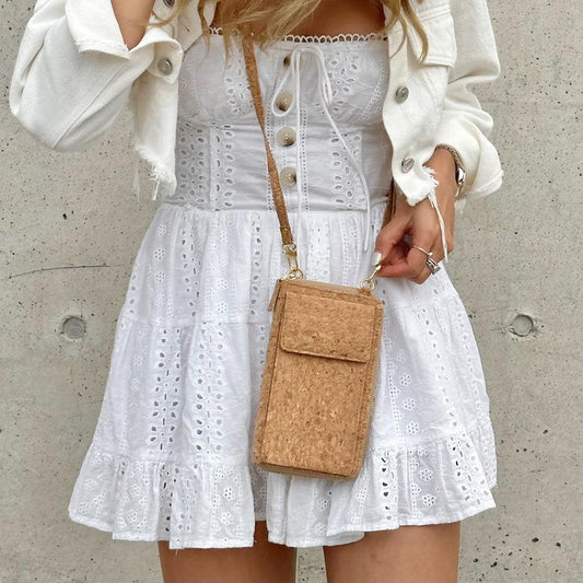 Model in white dress wearing By The Sea Collection, Nyla, classic cork cross body phone bag