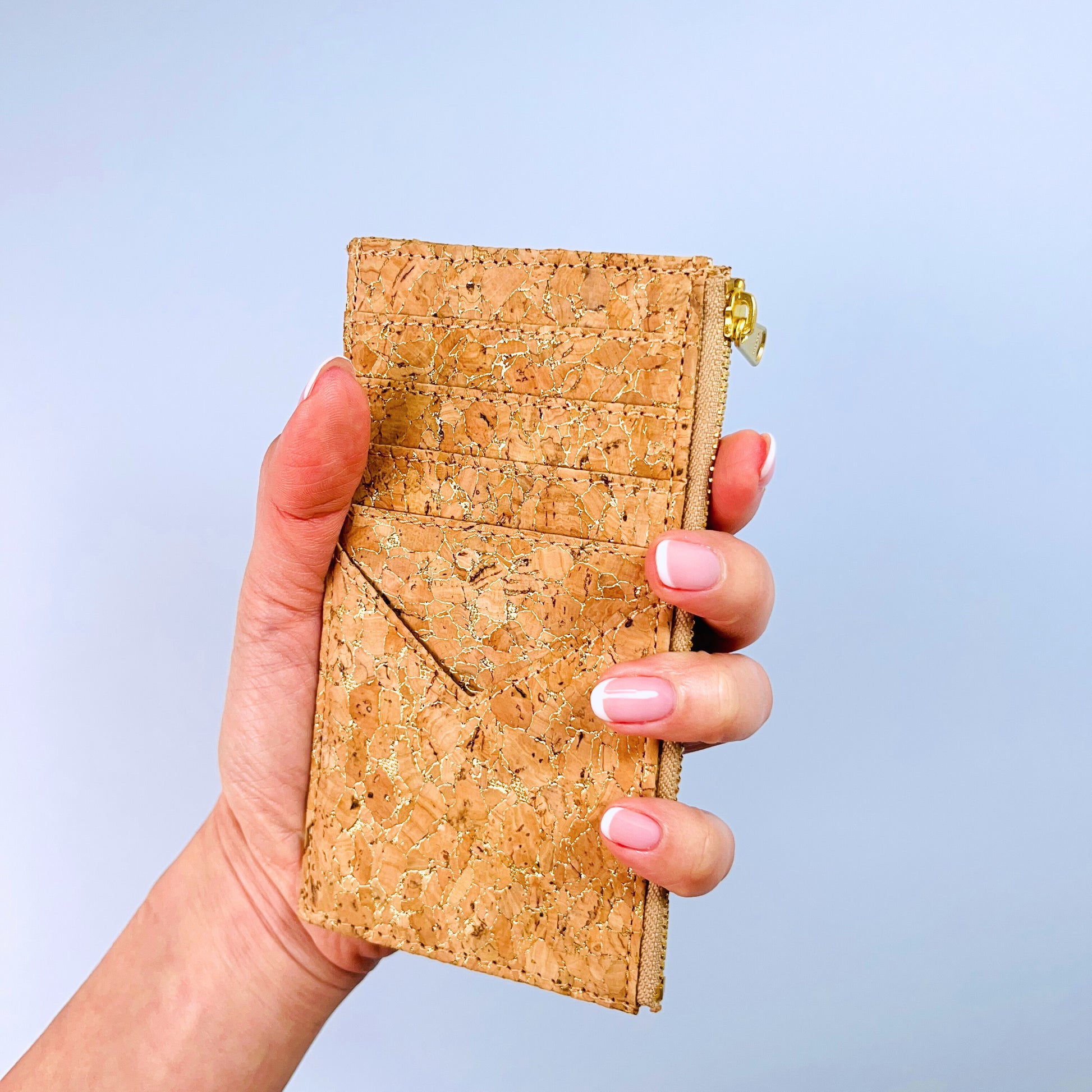 A woman's hand holding By The Sea Collection, Bernie, vegan cork leather card holder in gold