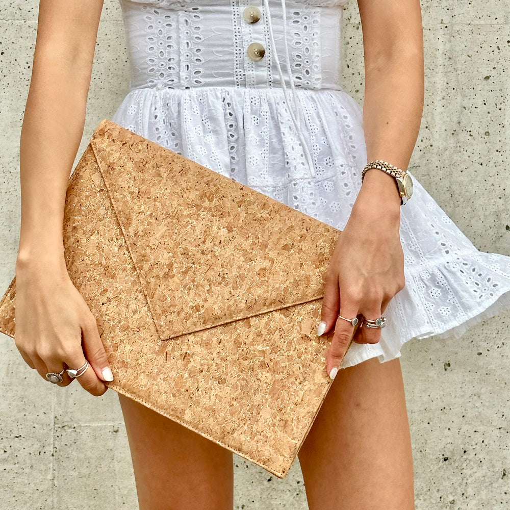 Model in white dress holding By The Sea Collection, Alice, gold vegan cork leather laptop document case