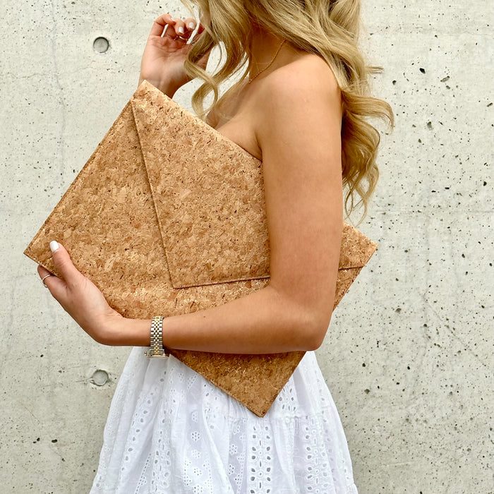 Model holding in between her arms By The Sea Collection, Alice, gold vegan cork leather laptop document case