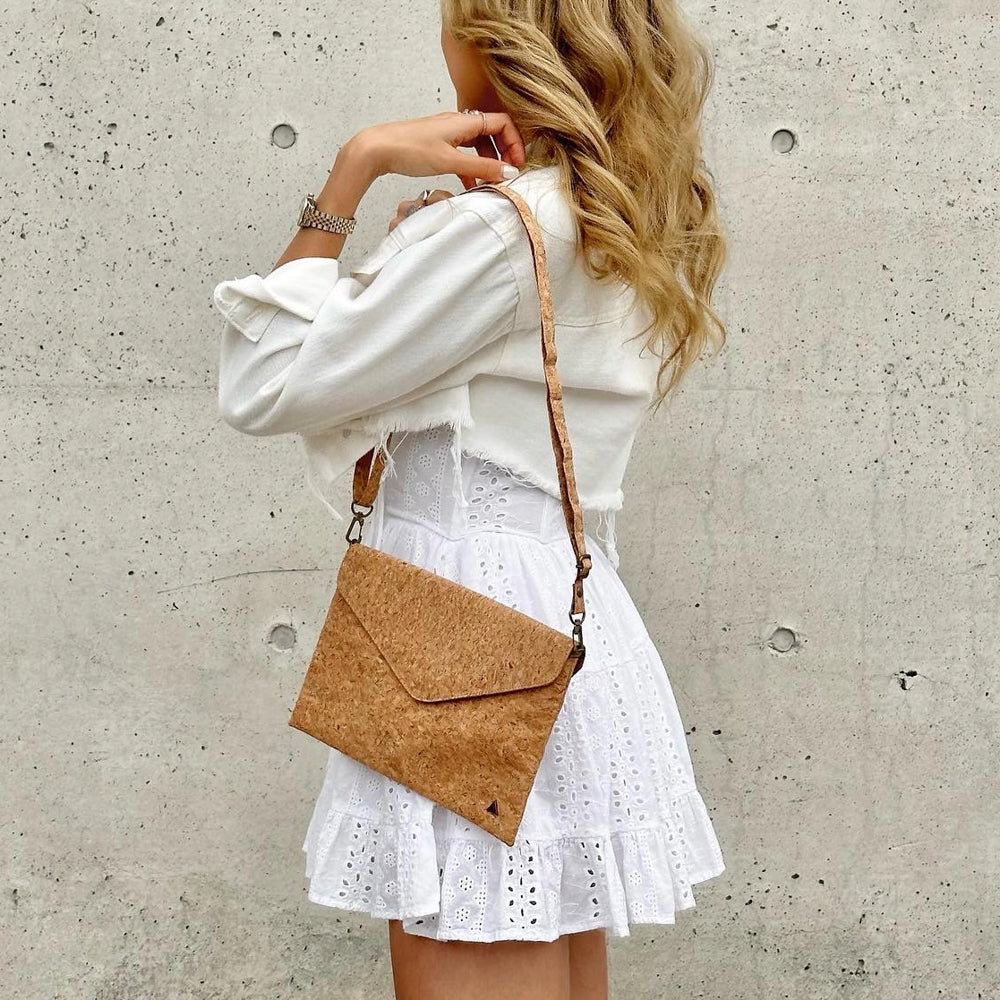 Model in white dress wearing shoulder bag style of By The Sea Collection, Aurora, classic vegan cork leather shoulder bag, clutch bag