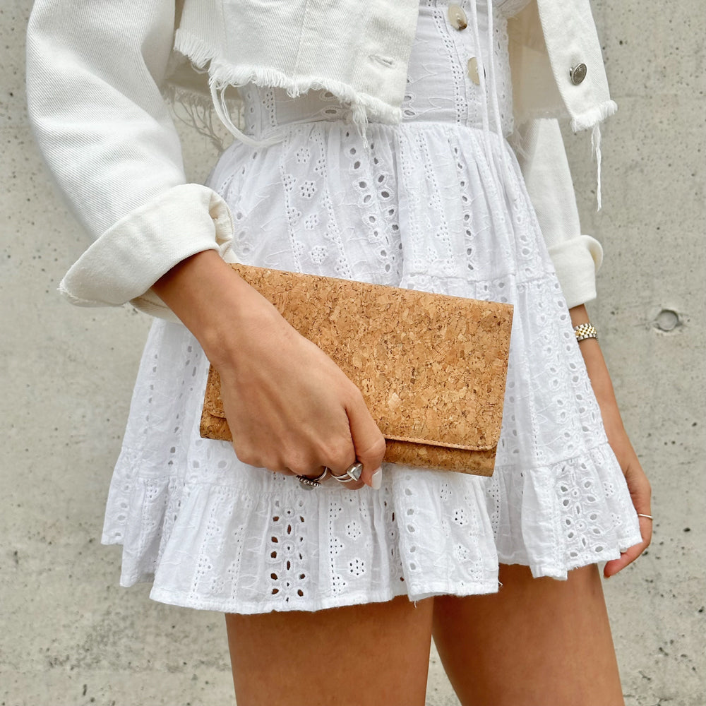 Half body shot of model holding By The Sea Collection, Lyla, classic vegan cork leather clutch