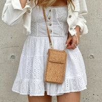 Model in white dress wearing By The Sea Collection, Nyla, classic cork cross body phone bag